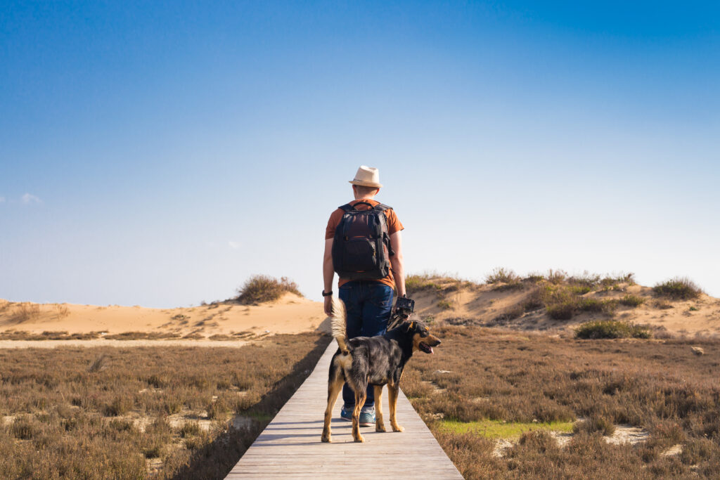 Outdoors lifestyle image of travelling man with cute dog. Tourism concept.