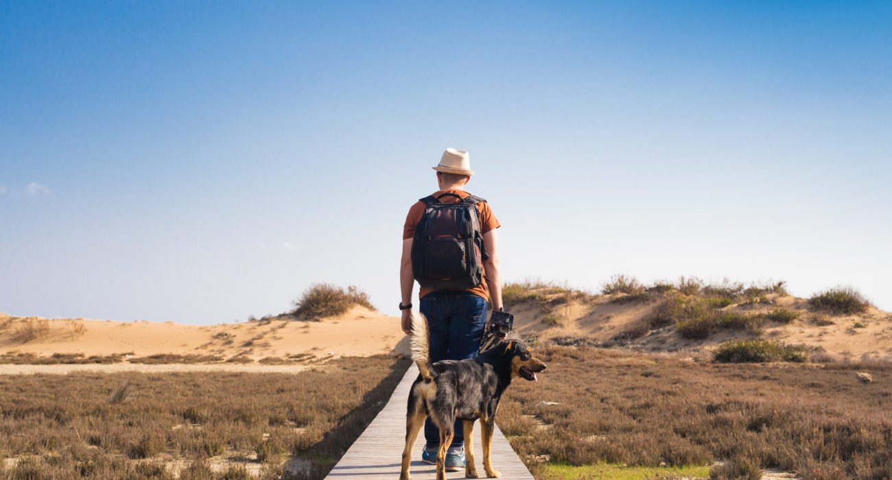 Outdoors lifestyle image of travelling man with cute dog. Tourism concept.
